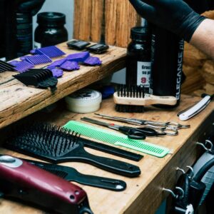 A detailed view of barber tools including scissors, combs, and more on a wooden barber shop counter.